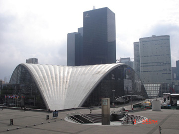 寬闊的廣場向四周_張開來，在大拱門左側宛若貝殼形式的 大建築物是法國國家工業及技術中心(C.N.I.T)國際展覽廳。
